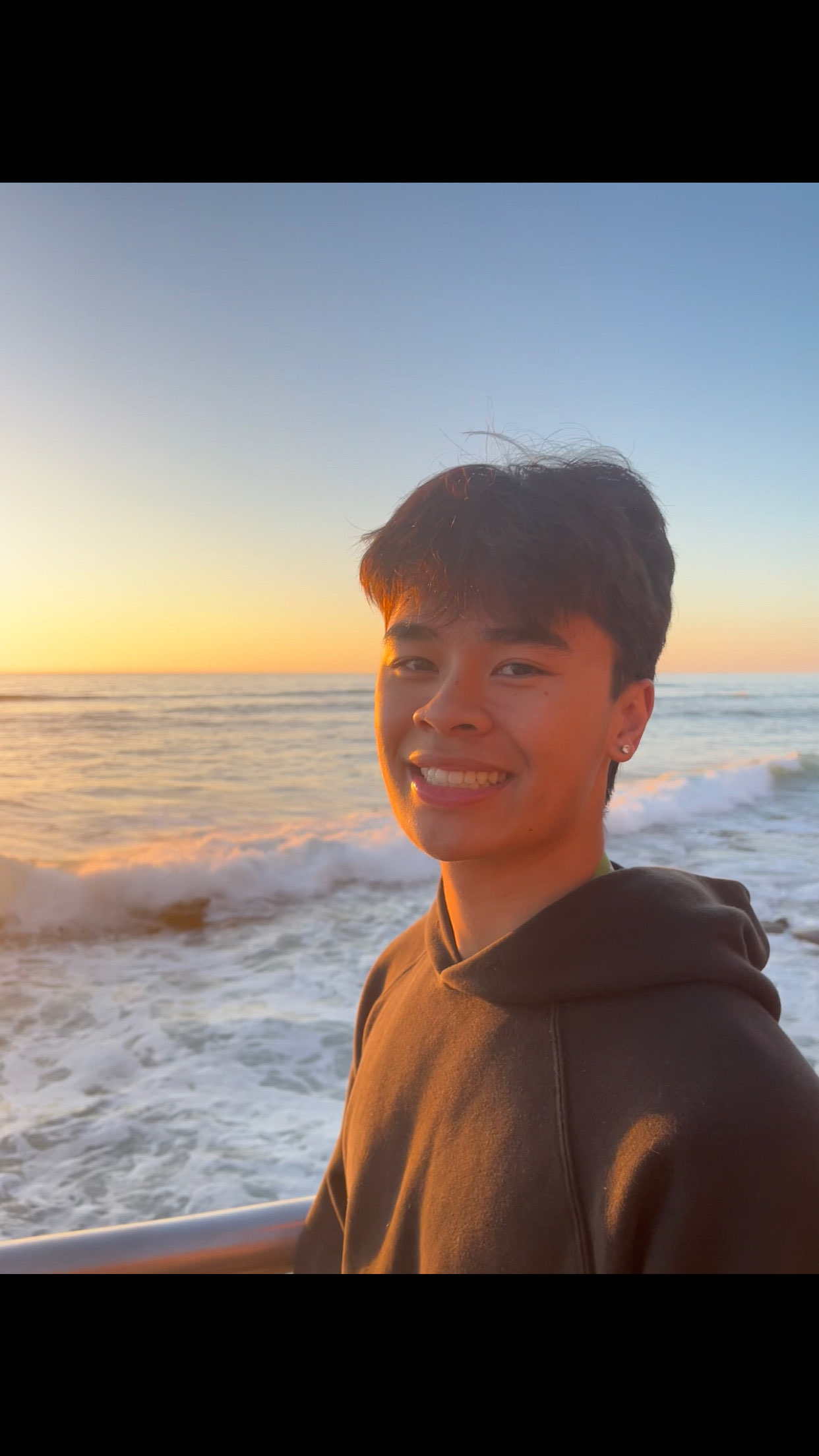 Tyler Nguyen smiling by the ocean at sunset